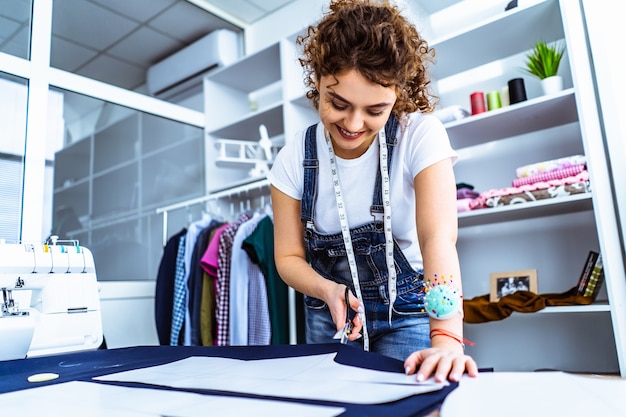 Premium Photo | The cute tailor sews a dress on the table