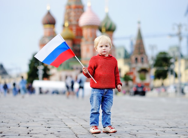 赤の広場とヴァシレフスキー降下とロシアの国旗を保持しているかわいい幼児男の子 プレミアム写真