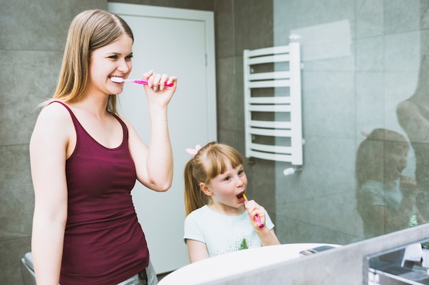Cute Woman And Girl Brushing Teeth Free Photo