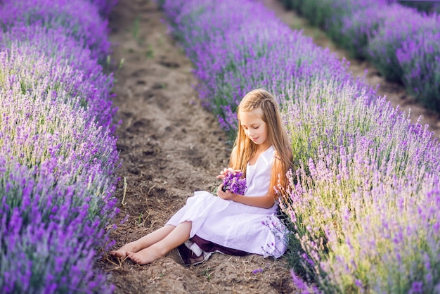 Premium Photo | Cute young girl collects lavender. a girl sits in ...