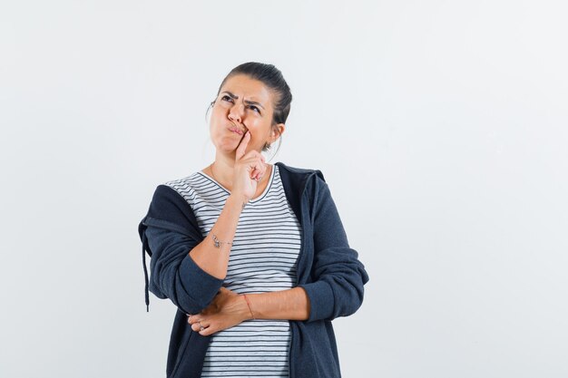 Free Photo | Dark-haired woman thinking with finger on her mouth in shirt