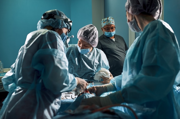 Premium Photo | Dark operating room, surgeons make a complex ...