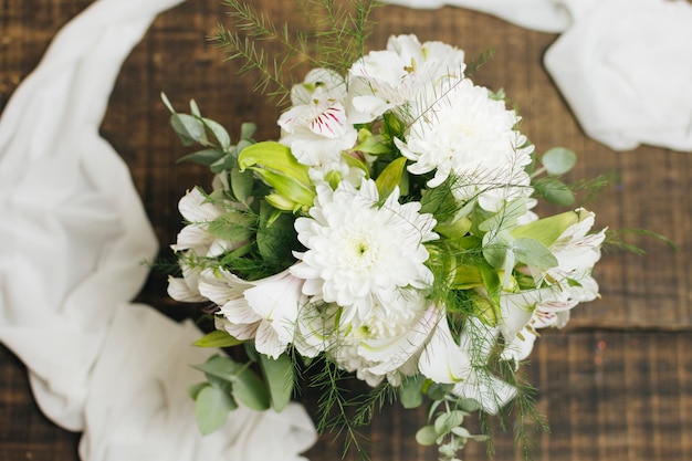 木製のテーブルの上のスカーフと装飾的な白い花の花束 無料の写真