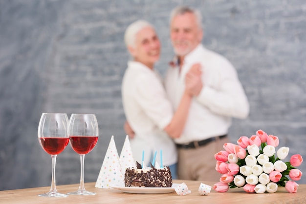 ワイングラスの前で踊る多重カップル 美味しいケーキ 木製のテーブルの上のチューリップの花 無料の写真