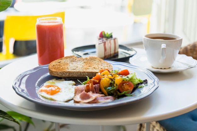 Delicious cake slice; breakfast; coffee cup and smoothie served on table Free Photo