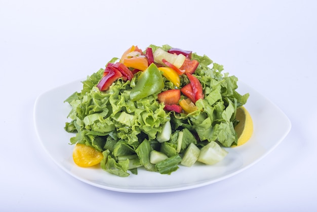 Delicious leafy vegetable salad on a white plate with slices of bell peppers on top Free Photo