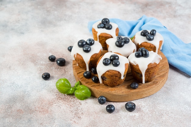 Delicious Vanilla Muffins In Sugar Fudge And Blueberries Are On The Board On The Right Horizontal Photo With Copy Space Premium Photo