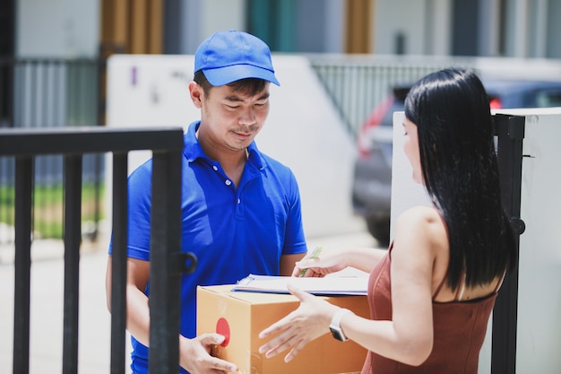 Premium Photo | Delivery man in a blue t-shirt holding carton box