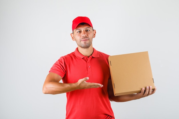 Delivery man showing pizza box in his hand in red uniform Free Photo
