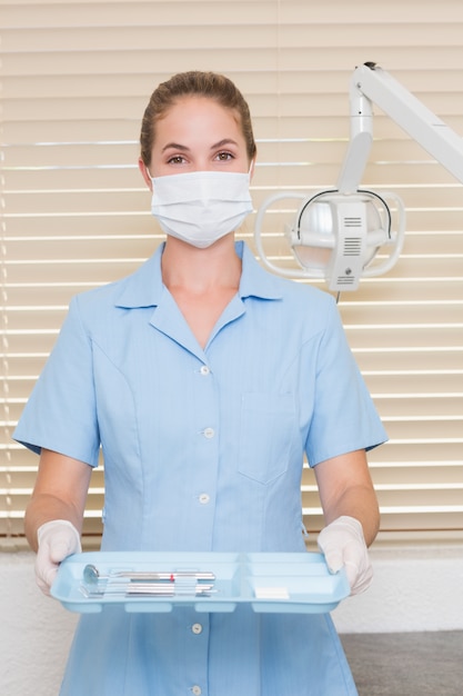 Premium Photo Dental Assistant In Mask Holding Tray Of Tools