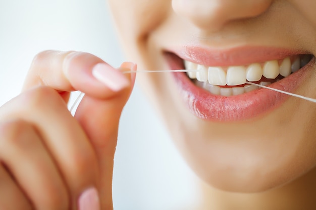 Dental care. woman with beautiful smile using floss for teeth.  image Premium Photo