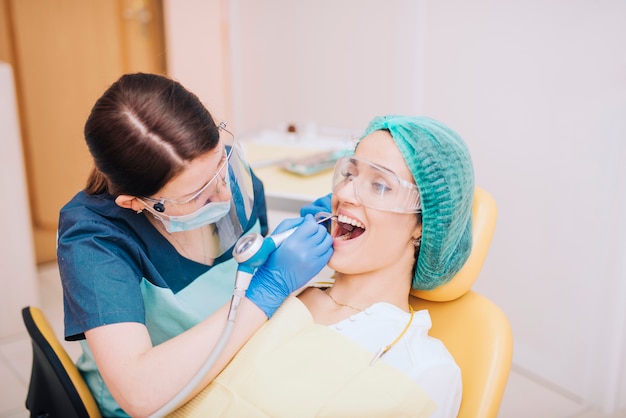 Dentist drilling teeth of female patient | Free Photo