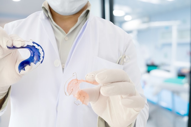 Dentist show dental retainer orthodontic appliance in his hand Premium Photo