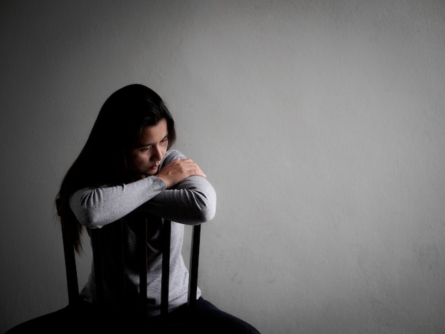 家の中の暗い部屋に一人で座ってうつ病の憂鬱な女性 孤独 悲しい 愛 プレミアム写真