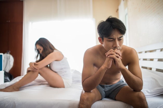 Depressed man sitting on the bed in bedroom have problem with his wife Free Photo