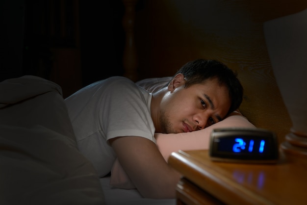 Depressed man suffering from insomnia lying in bed Premium Photo