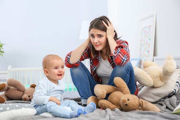 家でかわいい赤ちゃんと落ち込んでいる若い女性 プレミアム写真