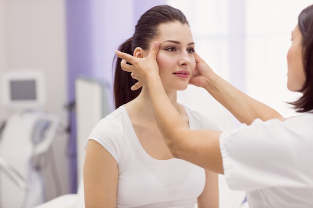 Dermatologist examining female patient skin