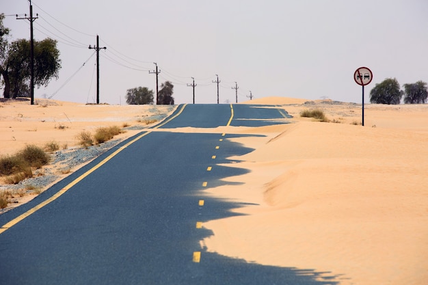 Premium Photo | Desert road with sand mound and sign about one way driving