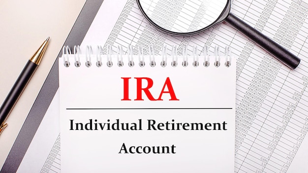 Desktop magnifier, reports, pen and notebook with text ira individual retirement account. business concept Premium Photo