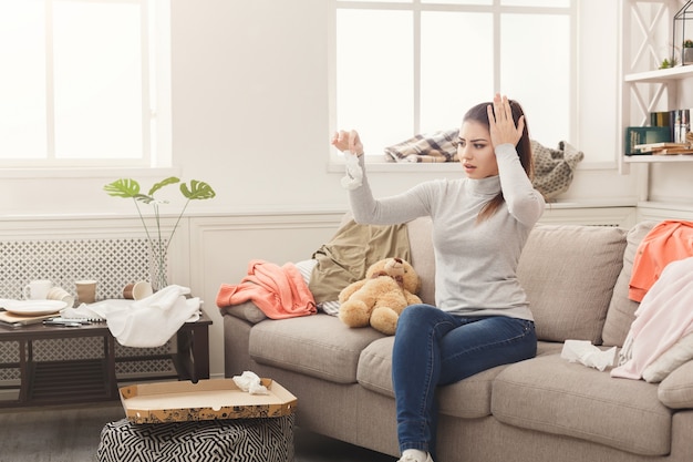 Premium Photo | Desperate woman sitting on sofa in messy room