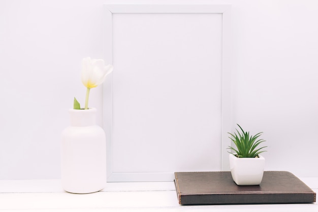 Diary; plant; tulip flower with blank photo frame on white table Free Photo