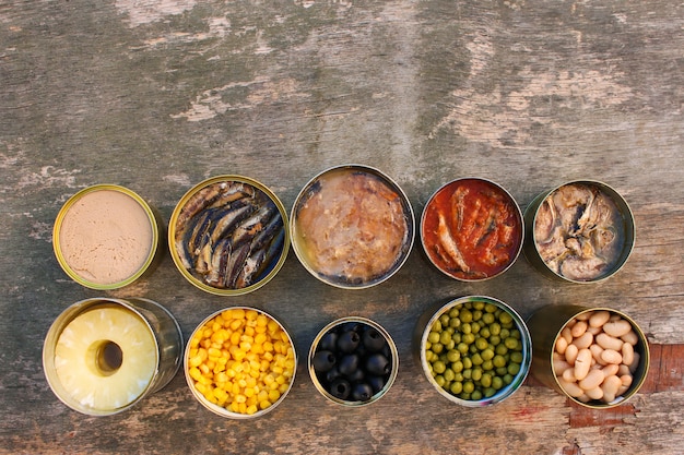 Premium Photo | Different open canned food on old wooden background