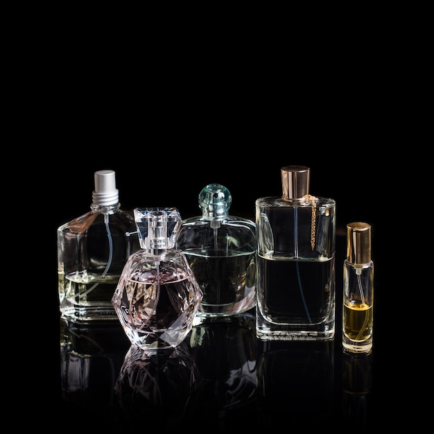 Premium Photo | Different perfume bottles with reflections on black surface