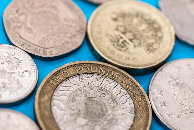 Premium Photo | Different pound coins on a blue background.