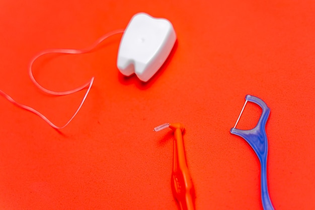 Premium Photo | Different types of dental floss and tooth picks on red ...