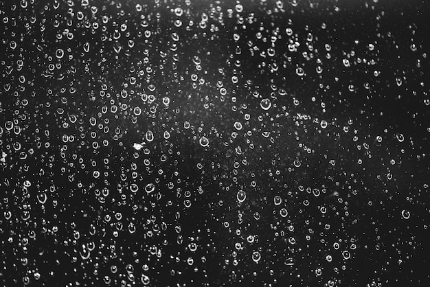 雨の滴で汚れた窓からす 雨滴と暗い雰囲気のモノクロ しずくと汚れがクローズアップ Copyspaceのマクロで詳細な透明なテクスチャ 夜の雨の天気 プレミアム写真