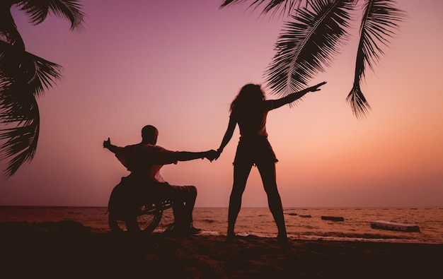 Premium Photo Disabled man in a wheelchair with his wife on the beach ...