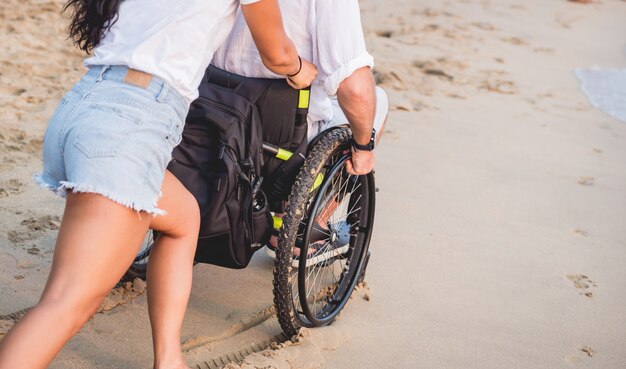 Premium Photo Disabled man in a wheelchair with his wife on the beach.