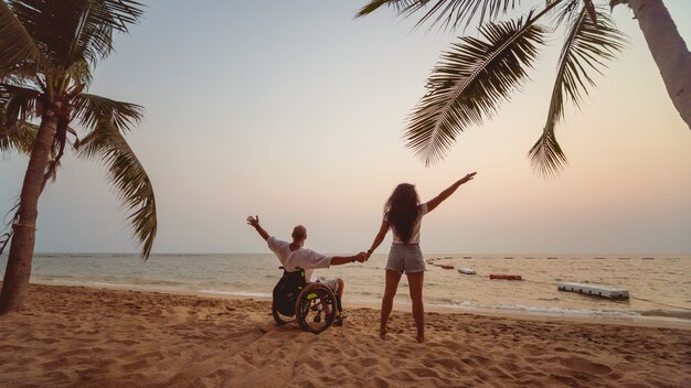 Premium Photo Disabled man in a wheelchair with his wife on the beach. image