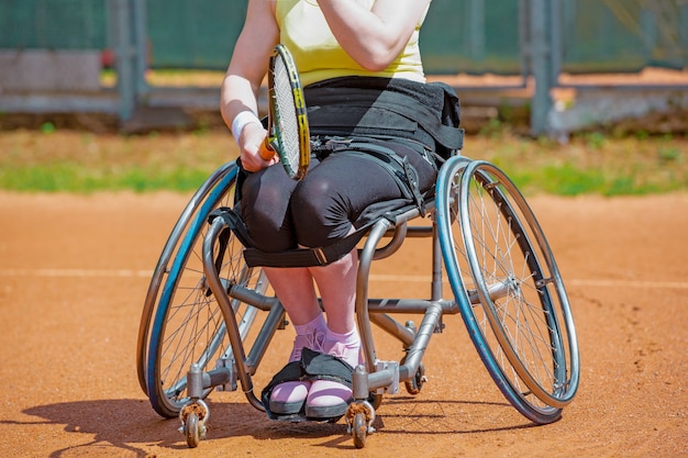 テニスコートでテニスをしている車椅子の障害のある若い女性 プレミアム写真