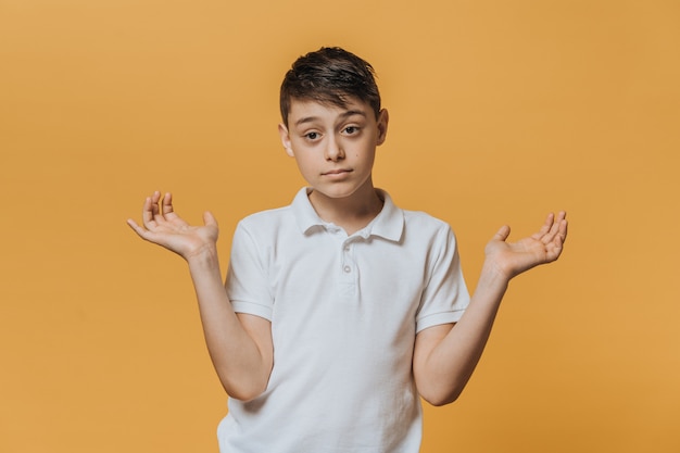 Premium Photo | Disappointed young boy in a white t-shirt spreads his ...