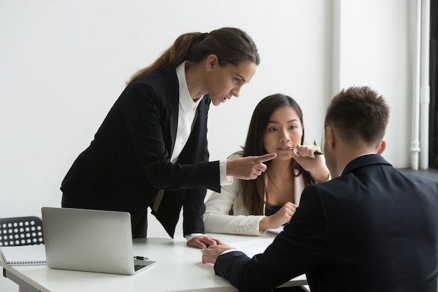 Dissatisfied female executive blaming threatening male employee at team meeting Free Photo