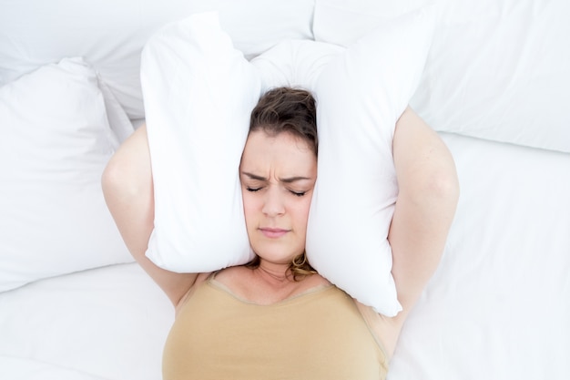 Dissatisfied Lady Covering Ears With Pillow in Bed Free Photo