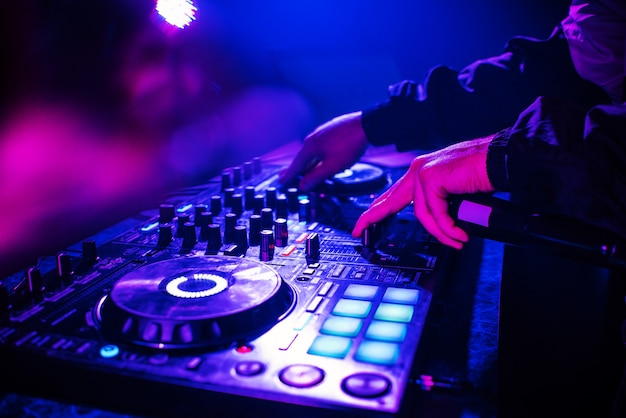 Dj console for mixing music with hands and with blurred people dancing ...