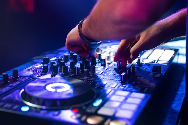 Dj hands mix music on a mixing board in a nightclub ...