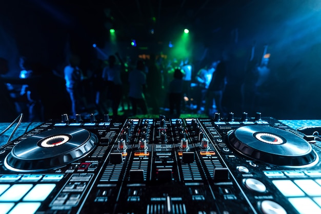 Premium Photo | Dj music mixer in a booth in a nightclub on a blurred ...