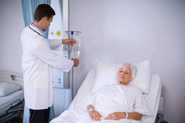 Premium Photo Doctor Adjusting Iv Drip While Patient Lying On Bed