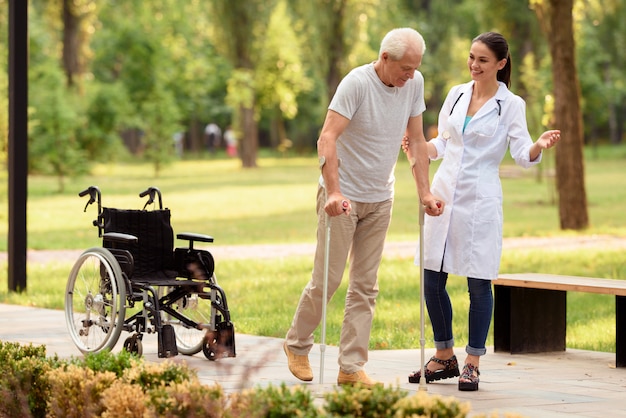 Premium Photo | The doctor helps the patient to walk on crutches.