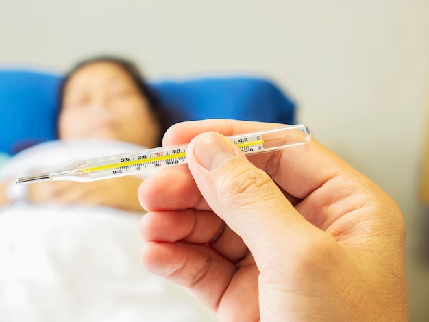 A doctor is looking at thermometer for measuring body temperature of his patient. Free Photo