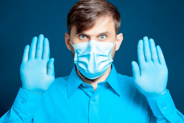 Premium Photo Doctor In A Medical Mask And Gloves In A Blue Uniform Gestures With His Hands