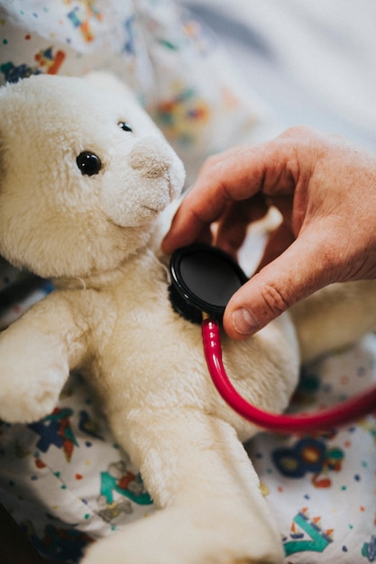 Doctor playfully checking the heart beat of a teddy bear Free Photo