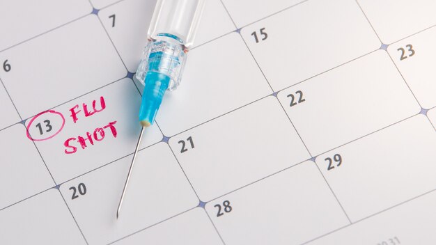 Doctor reminder flu shot in calendar with syringe, medicine and vaccine concept Premium Photo