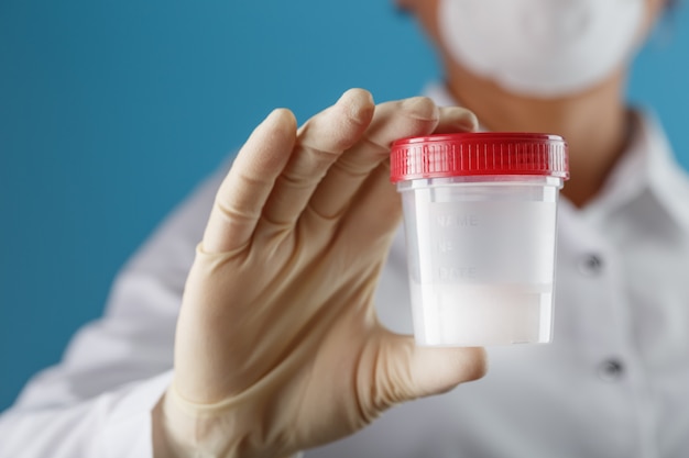 Premium Photo | A doctor's gloved hand holding a bottle of a container ...