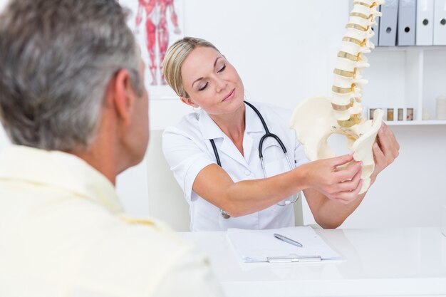 Premium Photo | Doctor showing her patient a spine model