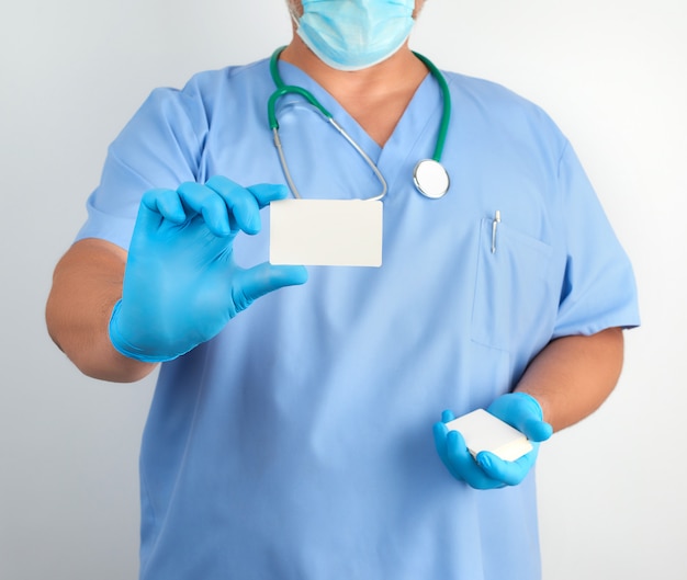Doctor In Sterile Latex Gloves And Blue Uniform Holds A Blank White